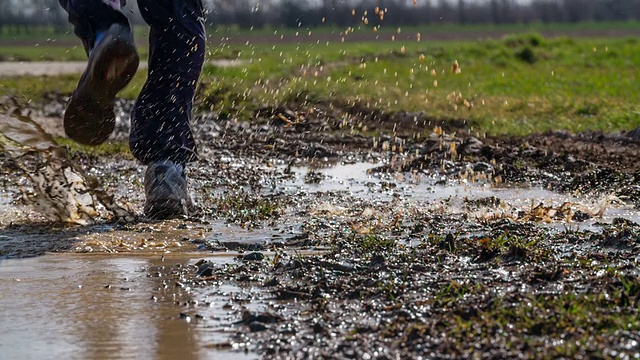 慢镜头:一个男人跑过泥泞的水坑视频素材