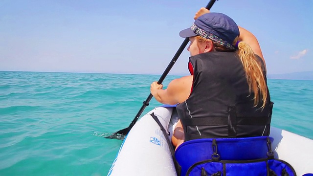 年轻女子在蓝色的海面上划皮艇视频素材