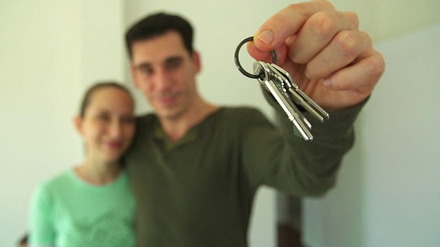 一对迷人的夫妇展示新房子的钥匙。(专注于按键)视频下载