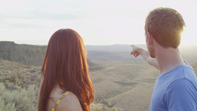 微笑的夫妇望着沙漠峡谷，拥抱在夕阳下视频素材
