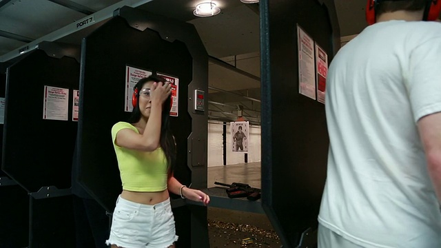 年轻貌美的亚洲女子在室内射击场用AR-15突击步枪射击视频素材