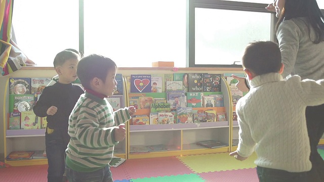 亚洲幼儿园老师在教室里和孩子们玩游戏，慢动作。视频下载