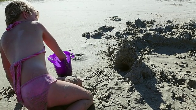 小女孩在美国乔治亚州圣西蒙斯岛的海滩上建造沙堡视频素材