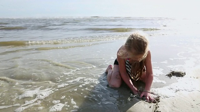 小女孩在美国乔治亚州圣西蒙斯岛的海滩上建造沙堡视频素材