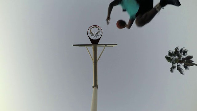低角度蠕虫眼睛的观点，一个年轻人打篮球在海滩上。视频下载