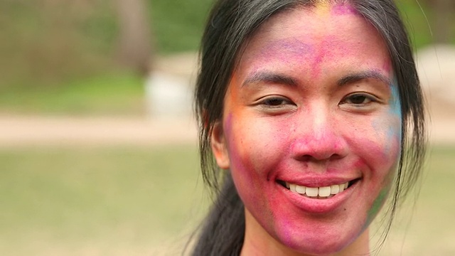 一个年轻女孩的肖像，脸上抹着彩粉微笑着。视频素材