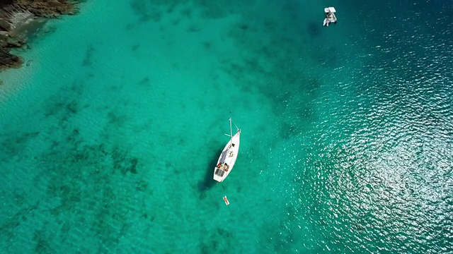 一艘单桅帆船抛锚停泊在加勒比海海湾的航拍视频视频素材