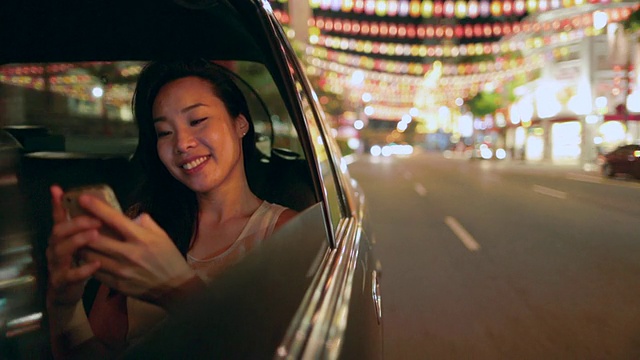 一个年轻的亚洲女人晚上在车里发短信。视频素材