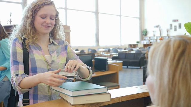 高中女生用借书证在图书馆的借书柜台借书视频素材