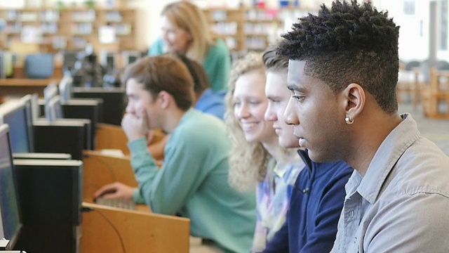 不同的公立高中学生在图书馆或计算机实验室的台式电脑上学习视频下载