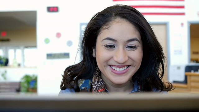 成年西班牙裔女学生在大学图书馆的电脑上打字视频素材