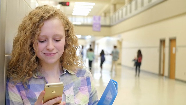 漂亮的白人少女金发卷发短信在高中视频素材