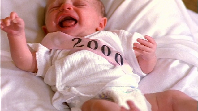 刚出生的女婴戴着粉色的“2000”饰带躺在白色垫子上哭泣视频下载