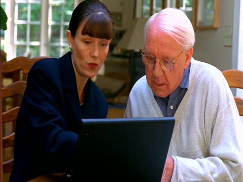 女顾问拿着笔记本电脑递文件，与坐在桌边的资深男士握手视频下载