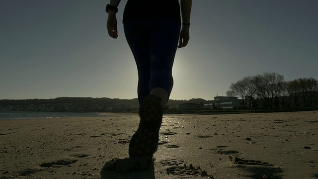 在沙滩上散步的女孩，身后是太阳视频素材