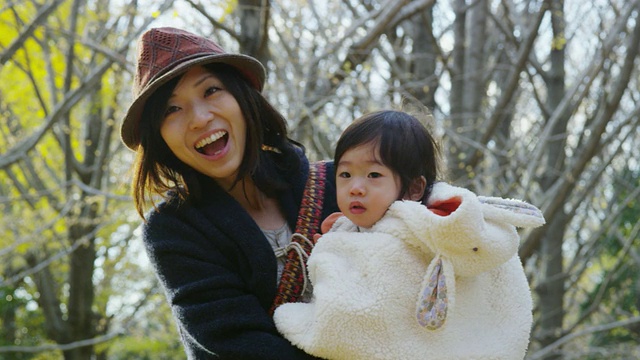 年轻的日本母亲与她1岁半的女儿在公园里玩得很开心视频素材
