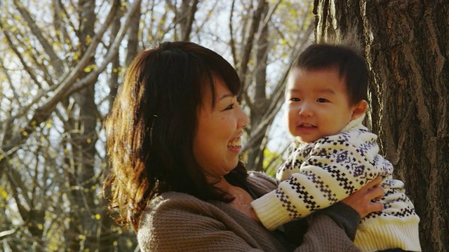 年轻的日本母亲与她1岁半的儿子在公园里玩得很开心视频素材