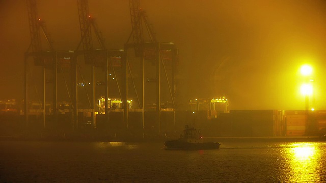 起重机和拖船在晚上停靠在港口视频素材