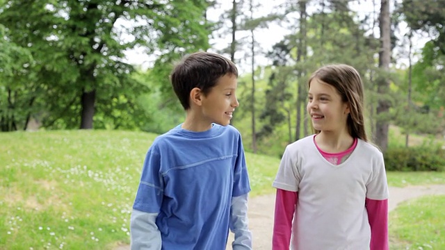 两个可爱的孩子在公园里散步。视频素材