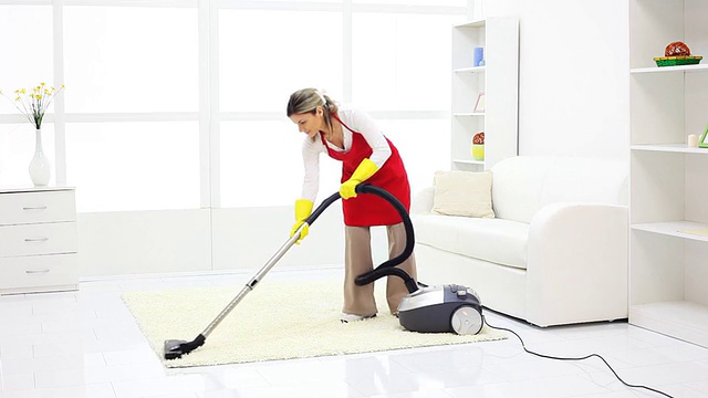用吸尘器清扫客厅的女人。视频下载