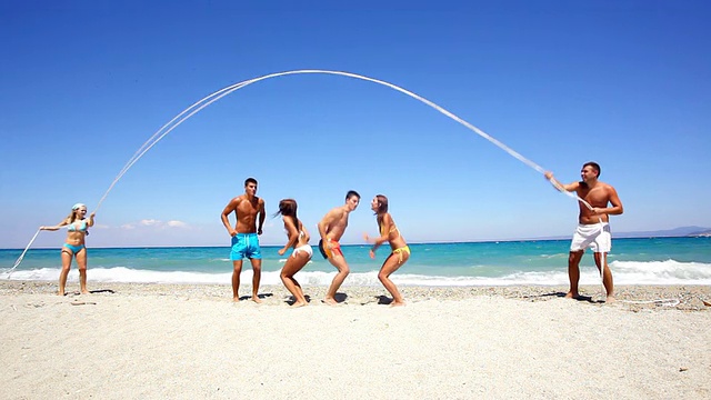 一群在海滩上蹦蹦跳跳的年轻人。视频下载