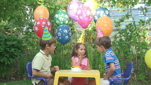 三个孩子在花园里参加生日聚会视频素材