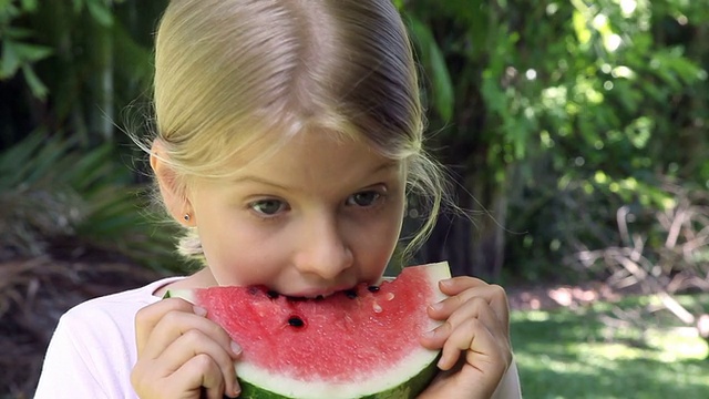 微笑的小女孩吃红色的西瓜水果在户外视频素材