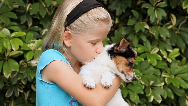 小女孩在花园里抱着一只小狗视频素材