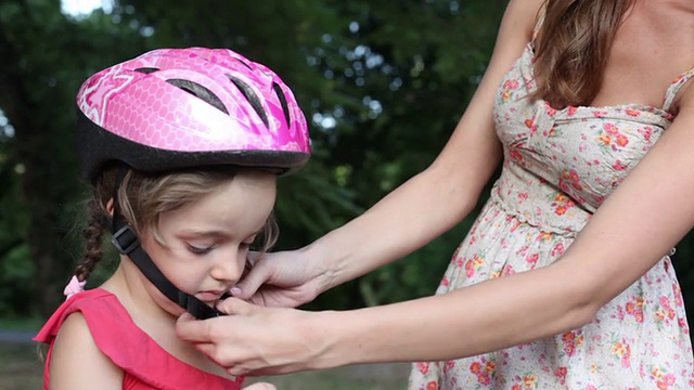 母亲帮助孩子与自行车头盔。视频素材
