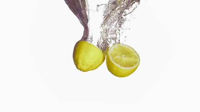 高清超级慢动作:切了一半的柠檬溅进水里视频素材