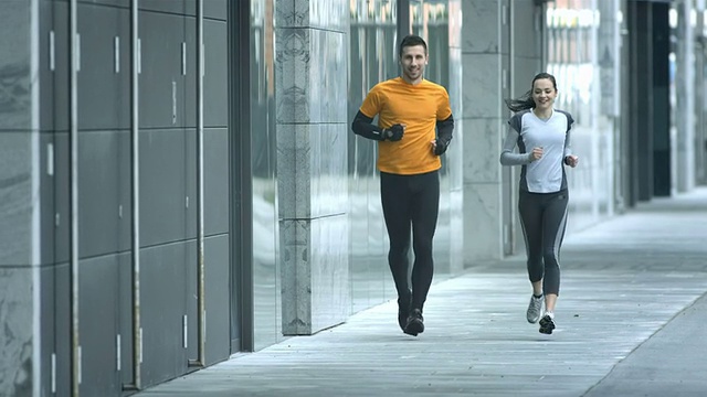 高清慢镜头:情侣沿人行道慢跑视频素材