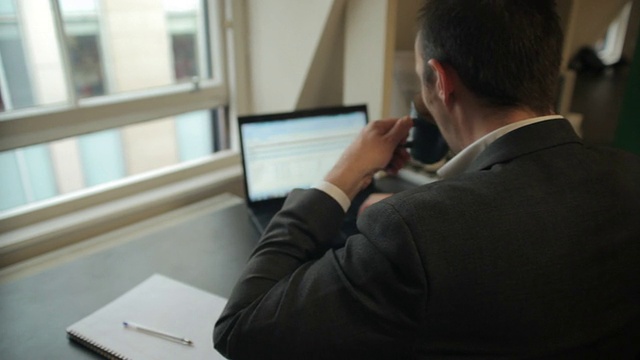 经理在用笔记本电脑工作，靠窗边喝咖啡视频素材