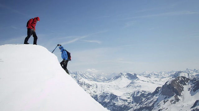攀登者互相帮助到达白雪覆盖的山峰视频素材