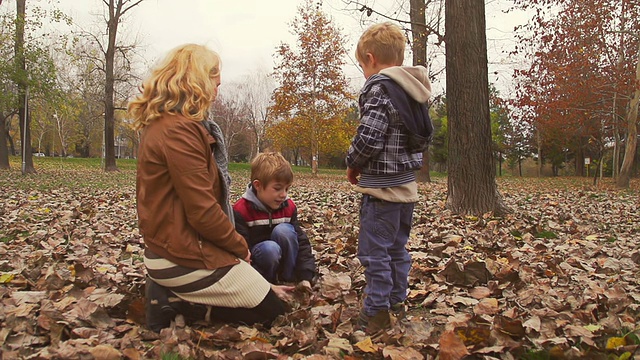 妈妈和孩子们在玩秋天的树叶视频素材