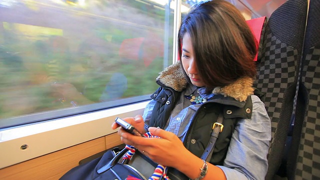 HD:年轻的亚洲女子在乘客列车上发短信视频素材