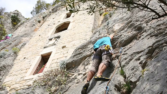 攀岩者攀登悬崖下的岩壁视频素材