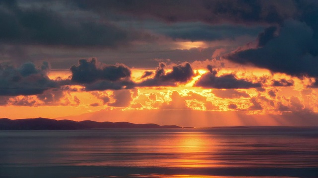 过度曝光的日落时间，太阳燃烧海面上的云视频下载