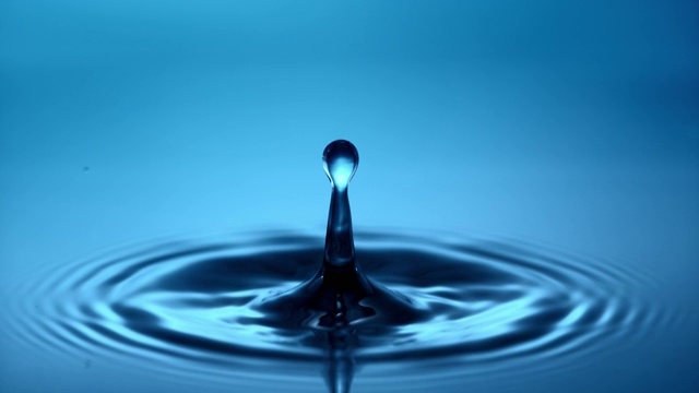 一滴水滴落进蓝色的水里视频素材