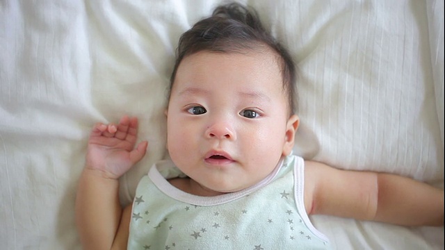 亚洲婴儿躺在白色的床上视频素材