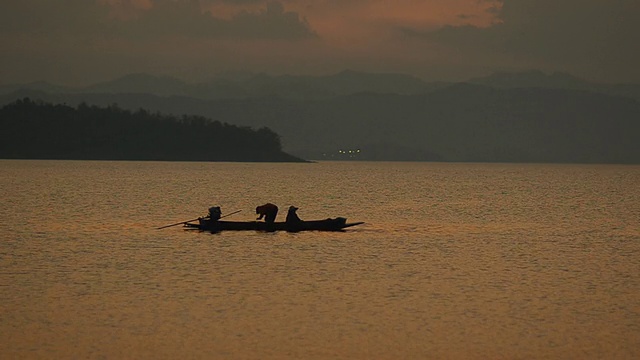 画面:黄昏时分，渔民在大坝上的长船上捕鱼视频下载