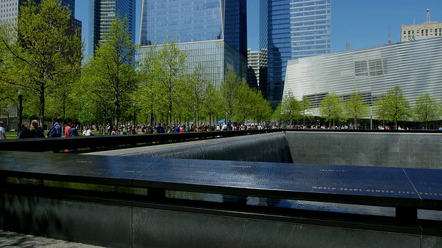 TU的相机捕捉到了911纪念公园里被新鲜的绿树环绕的纪念南池和自由塔。自由塔在阳光下闪耀。左边是环球金融中心。视频素材