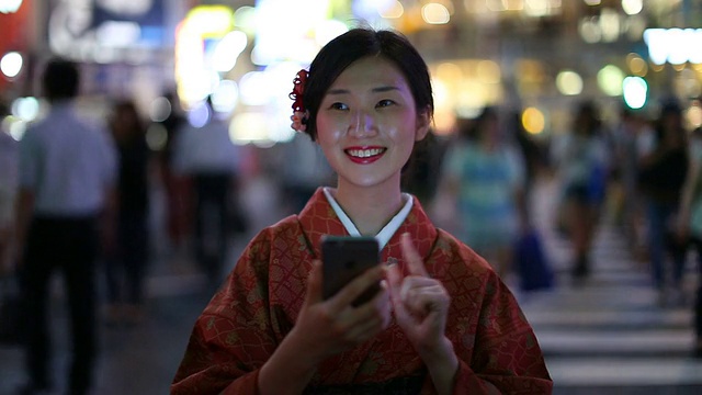 日本女孩穿着和服发短信和微笑在涉谷视频素材