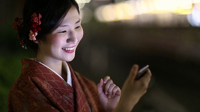 身着和服的日本女孩晚上在涉谷发短信视频素材