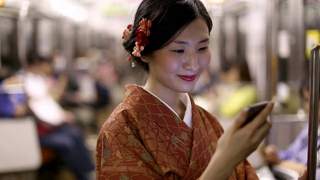 穿着和服的日本女孩在地铁里给她的朋友发短信视频素材