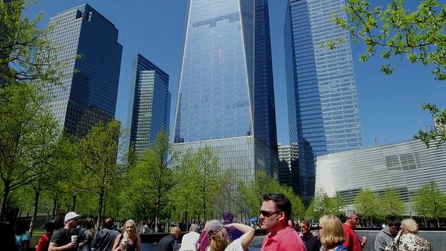 TU的相机捕捉到了911纪念公园里被新鲜的绿树环绕的纪念南池和自由塔的人们。自由塔在阳光下闪耀。左边是环球金融中心。视频素材
