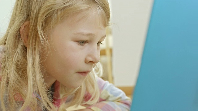 小女孩在笔记本电脑上看书视频素材