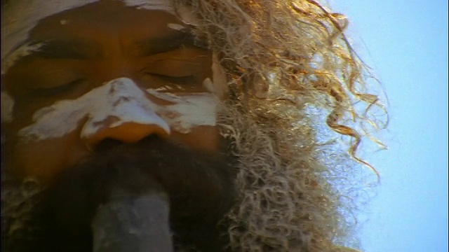 镜头拉近，澳大利亚新南威尔士州蓝山，一名面部涂着白色油漆、正在演奏迪吉里杜管的男性土著居民视频素材