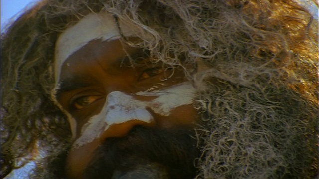慢镜头拉近镜头，一名面部涂着白漆、正在演奏迪吉里杜管(澳洲蓝山)的土著男子视频素材