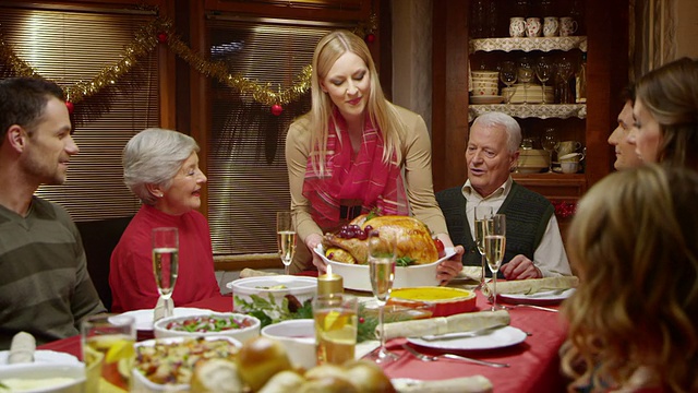 年轻女子把火鸡带到圣诞餐桌上视频素材