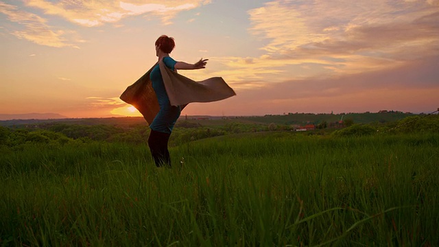 日落时分，快乐的女人在草地上纺纱视频素材